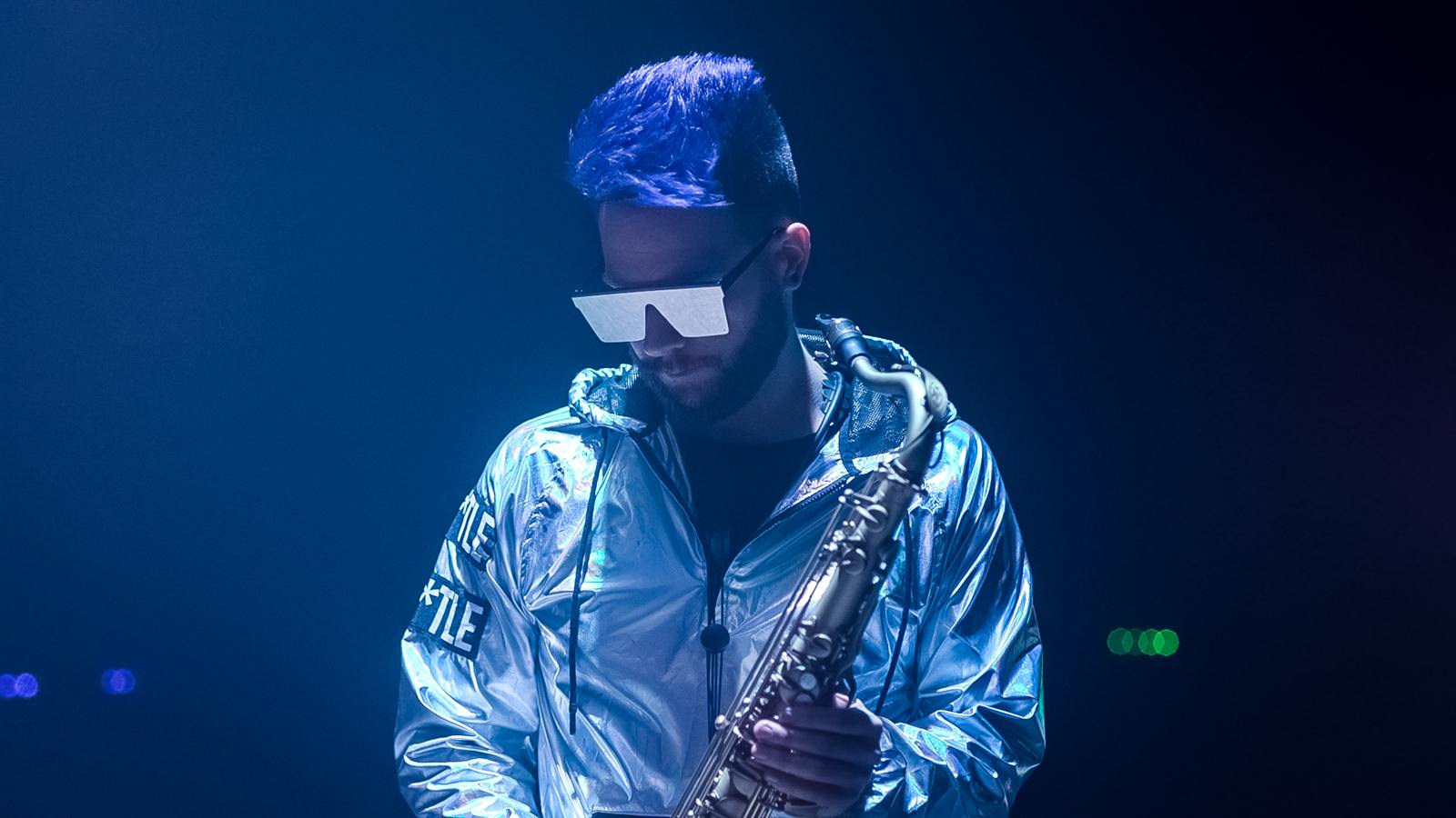 Lucas Sanor playing saxophone under stage light