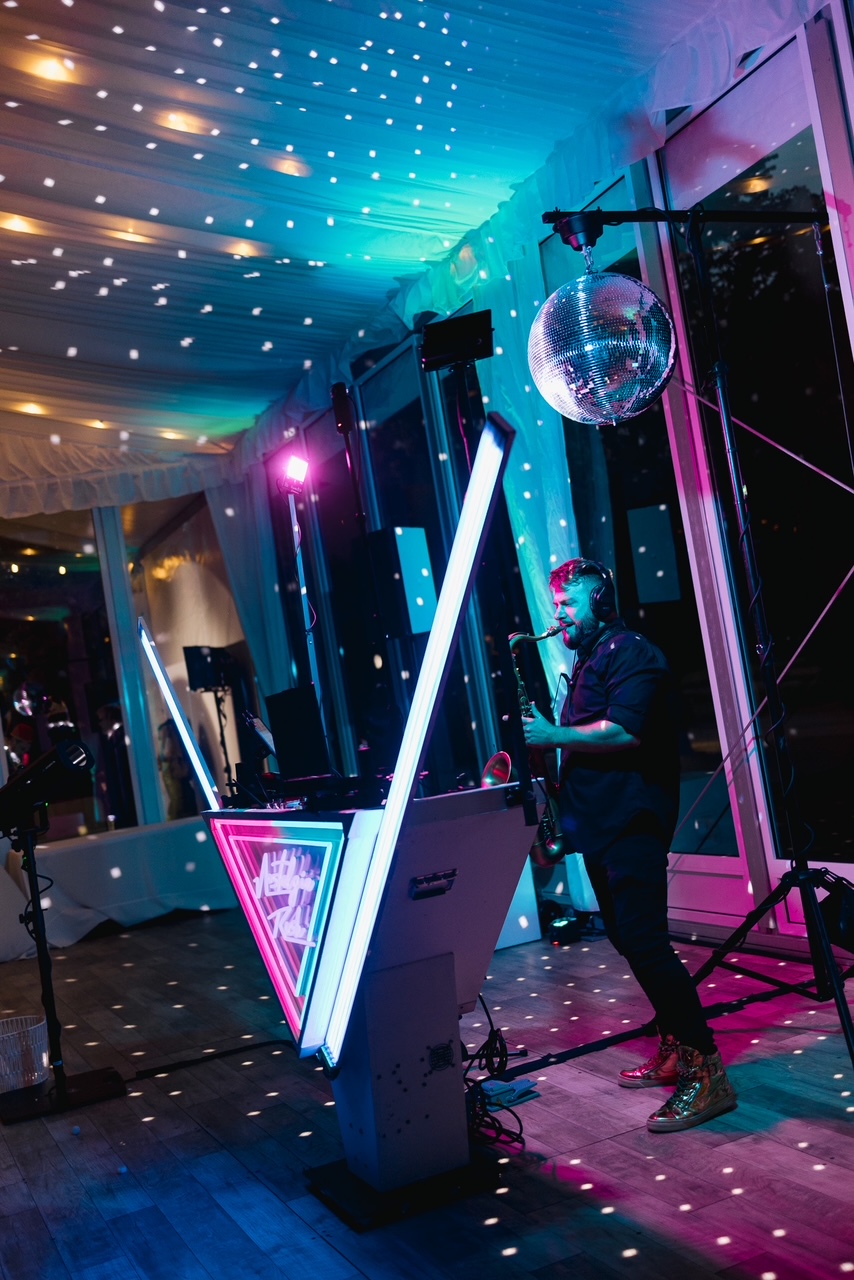 Full view of Lucas's DJ booth, disco ball, uplighting, and lighting rig — every piece of equipment in the package above